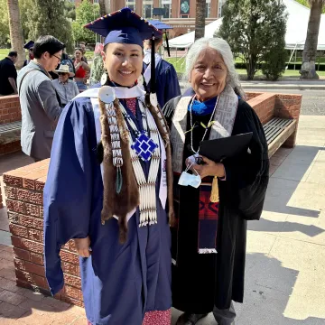 Rosalia Badhorse posing at graduation with Ofelia Zepeda.